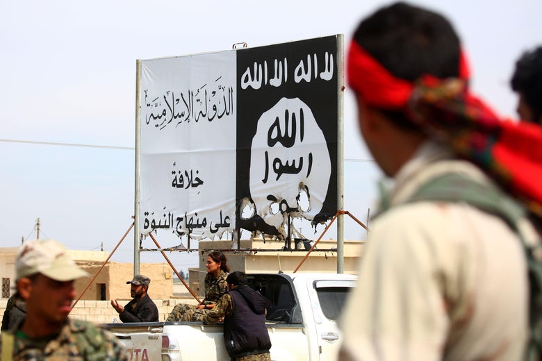 Members of the US-backed Syrian Democratic Forces (SDF), made up of an alliance of Arab and Kurdish fighters, stand under an Islamic State (IS) group banner in the recently recaptured town of Al-Karamah, 26 kms from the IS bastion of Raqa, on March 26, 2017.